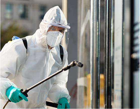 Worker in protective suit spraying disinfectant